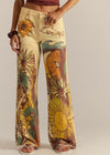 Person wearing pants with floral and abstract designs on a plain background