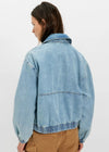 Person wearing a light blue denim jacket on a white background
