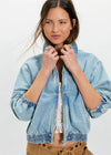 Woman wearing a light blue denim jacket on a white background
