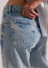 Close-up of blue jeans with a person wearing them, focusing on the pocket area.