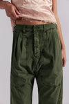 Person wearing green pants and a pink top on a plain background