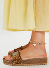 Brown platform sandals worn with a yellow skirt on a white background