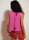 Person wearing a pink sleeveless top with a patterned skirt against a plain background