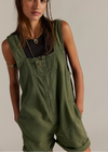 Woman wearing green overalls against a plain background