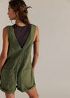 Woman wearing a green romper against a plain background