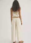 Woman wearing a cream-colored top and wide-leg pants on a white background