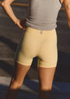 Person wearing beige shorts and a gray tank top with a blurred background