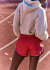 Person wearing a beige hoodie and red shorts on a track