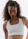 Woman wearing a white sports bra against a plain background