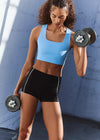 Woman exercising with dumbbells against a blue wall