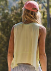 Person wearing a light green sleeveless top and pink cap in a natural setting