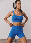 Person wearing a blue athletic outfit with headphones, standing against a plain background