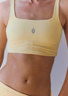 Yellow sports bra with a small logo on a plain background