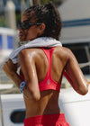Woman in red athletic outfit with towel around neck, possibly after exercise