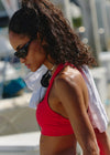 Woman in a red bikini with sunglasses and a white towel on a blurred background