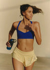 Woman in athletic wear holding a water bottle against a neutral background