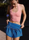 Woman in athletic wear with earphones, standing outdoors.