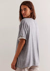 Woman wearing a gray oversized t-shirt against a plain background