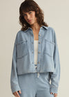 Woman wearing a light blue denim jacket and pants on a beige background