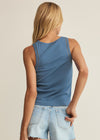 Person wearing a blue tank top and denim shorts on a beige background