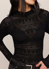 Black patterned sweater worn by a person on a neutral background
