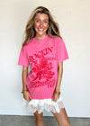 Woman wearing a pink t-shirt with red text and graphics against a white background