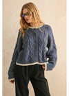 Woman wearing a blue knitted sweater with a beige background