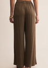 Brown wide-leg pants worn by a person on a beige background