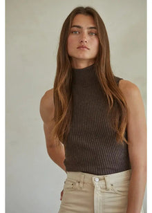  Woman wearing a brown ribbed tank top and beige pants against a plain background