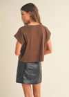 Woman wearing a brown top and black leather skirt on a beige background