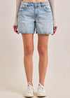 Denim shorts worn by a person on a plain background