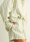 Green and white striped shirt worn by a person on a plain background