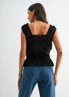 Woman wearing a black lace top and blue jeans on a white background
