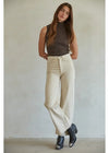Woman wearing a brown sleeveless top and beige high-waisted pants against a plain background