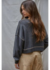 Woman wearing a dark denim jacket and beige pants against a plain background