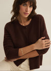 Woman wearing a brown sweater against a plain background