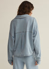 Person wearing a light blue denim jacket and pants on a beige background