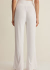 White ribbed pants worn by a person on a beige background