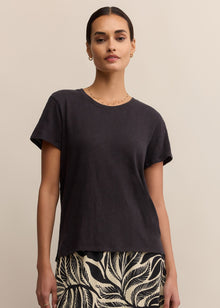  Woman wearing a black top and patterned skirt against a beige background
