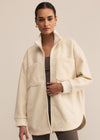 Woman wearing a cream-colored coat against a beige background