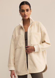  Woman wearing a cream-colored coat against a beige background
