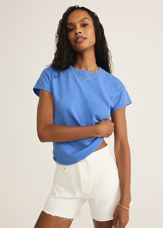 Woman wearing a blue t-shirt and white shorts against a plain background