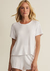 Woman wearing a white ribbed top and shorts set on a beige background