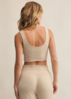 Person wearing a beige ribbed crop top and pants on a plain background