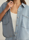 Light blue denim shirt worn by a person on a neutral background