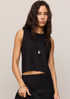 Woman wearing a black sleeveless top and black pants against a plain background