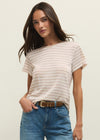 Woman wearing a striped shirt and blue jeans against a plain background