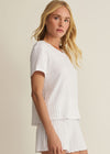 Woman wearing a white pleated outfit against a beige background