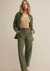 Woman wearing a green outfit with a beige top on a plain background
