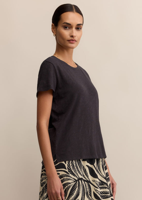 Woman wearing a black top and patterned skirt against a beige background